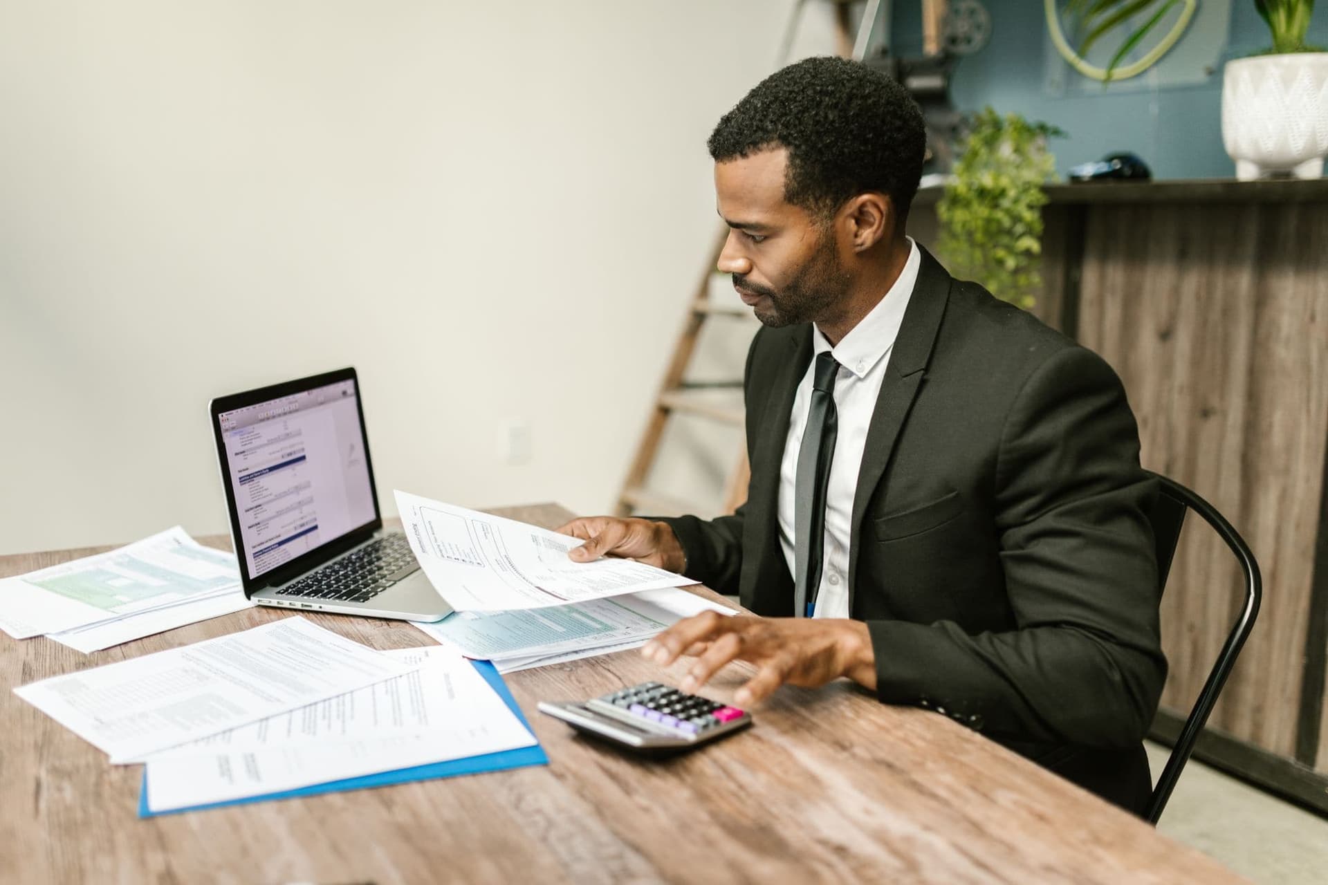 Finance professional working with invoices on a laptop and calculator