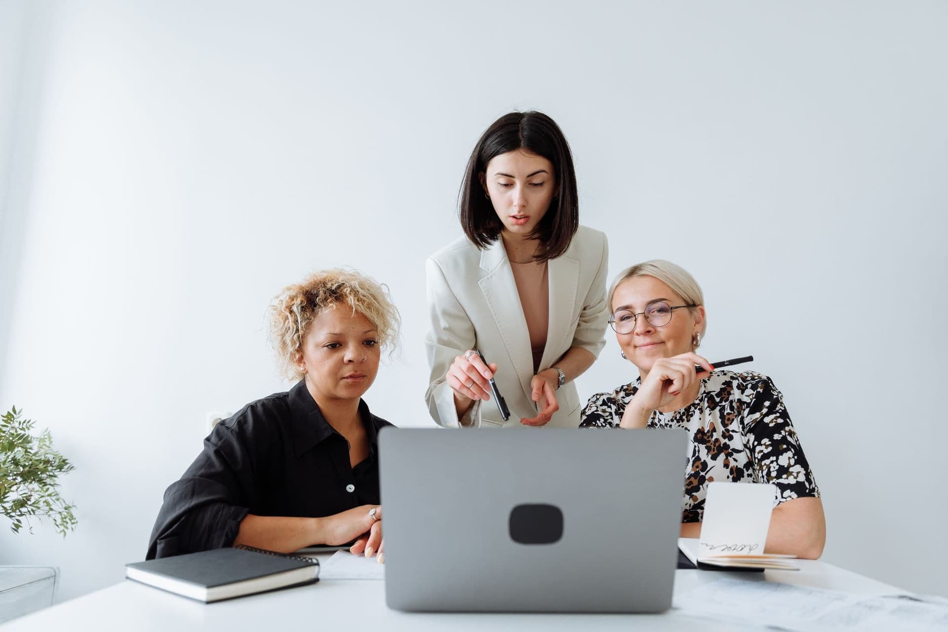 Three colleagues collaborating around a laptop in a bright office